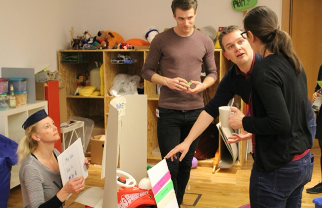 Workshop-Gruppe baut und diskutiert Prototyp mit Bastelmaterialien
