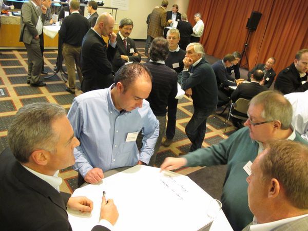 Workshop-Teilnehmer arbeiten in Kleingruppen an einem Tisch mit Flipchart-Papier
